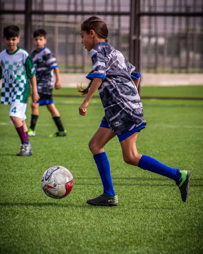 about-02 Young players engaged in a dynamic soccer match on a sunny day, showcasing youthful energy and teamwork.