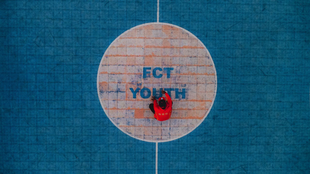 Drone shot of a person in red on FCT Youth sports court, Abuja, Nigeria.